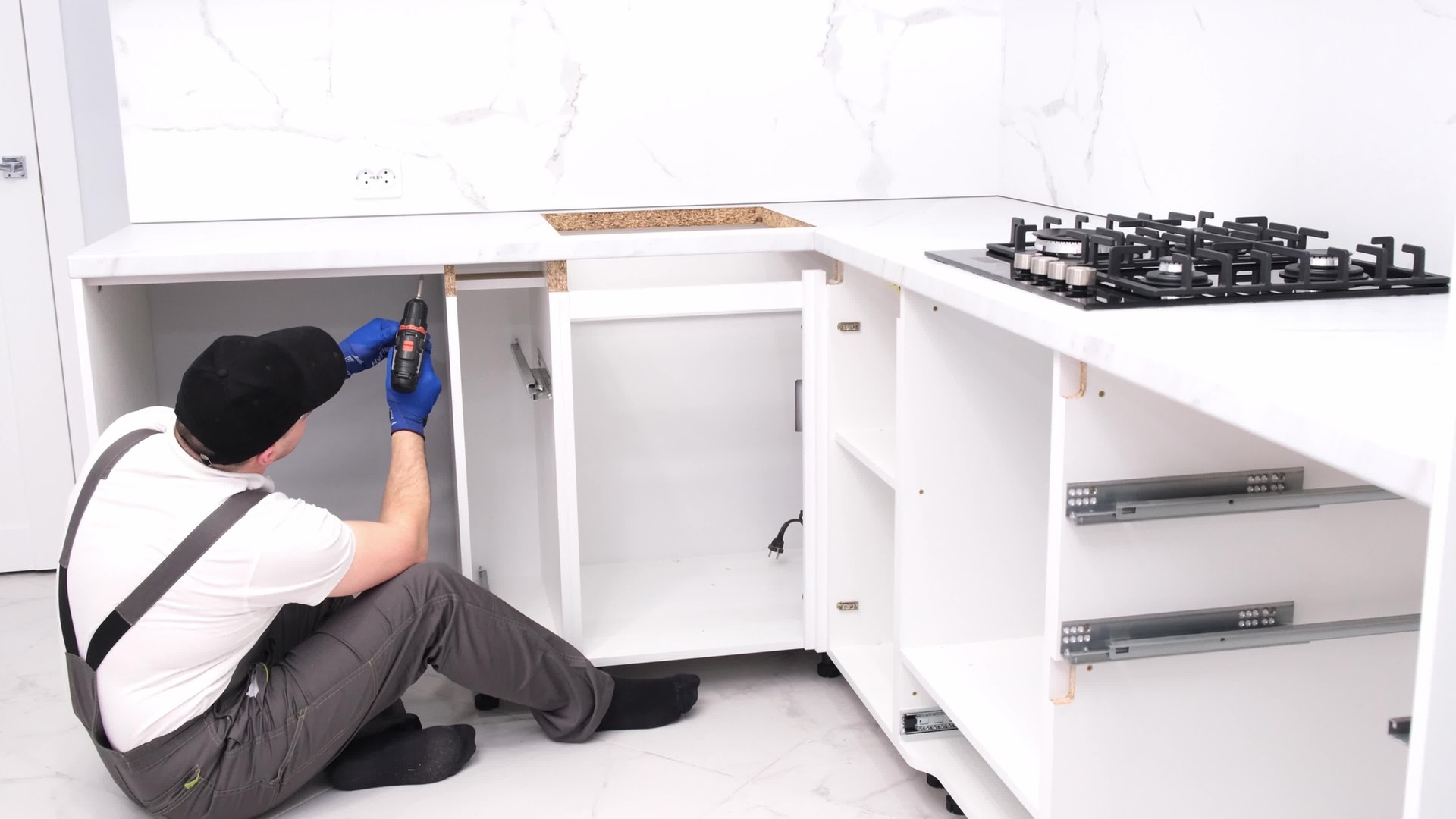 A craftsman in a black cap assembles furniture in the kitchen